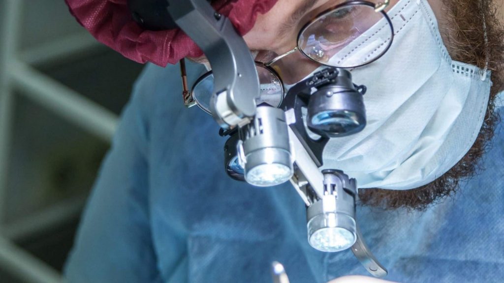 A surgeon wearing a surgical headlight while operating on a patient